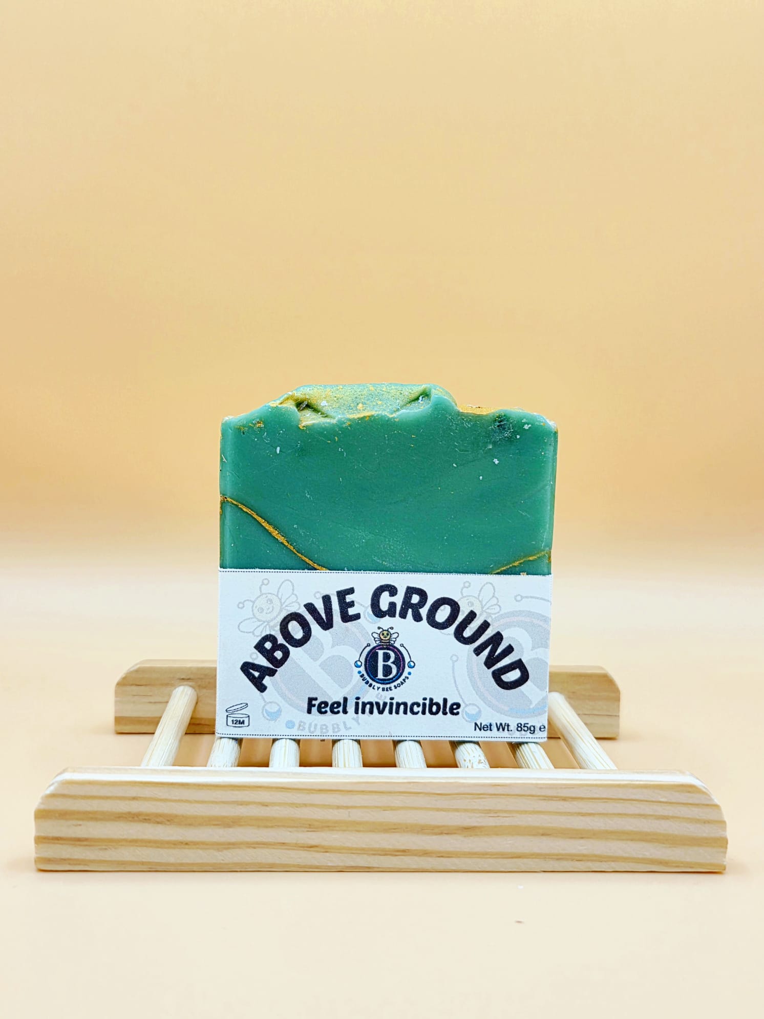 Green soap bar with 'Above Ground' label on a wooden stand against a beige background