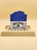 Blue bar of soap on a wooden stand with 'BEE COOL' label against a beige background