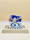 Bar of soap with a label on a wooden stand against a beige background