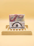 Bar of soap with 'Bubblegum Blast' packaging on a wooden stand against a yellow background