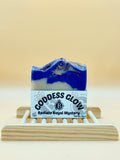Bar of soap with a label on a wooden stand against a beige background